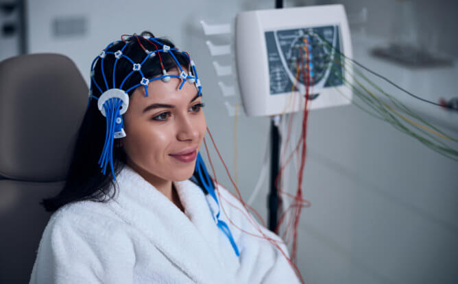A woman is sitting in a clinic while having an electroencephalogram EEG test to measure her brain activity.