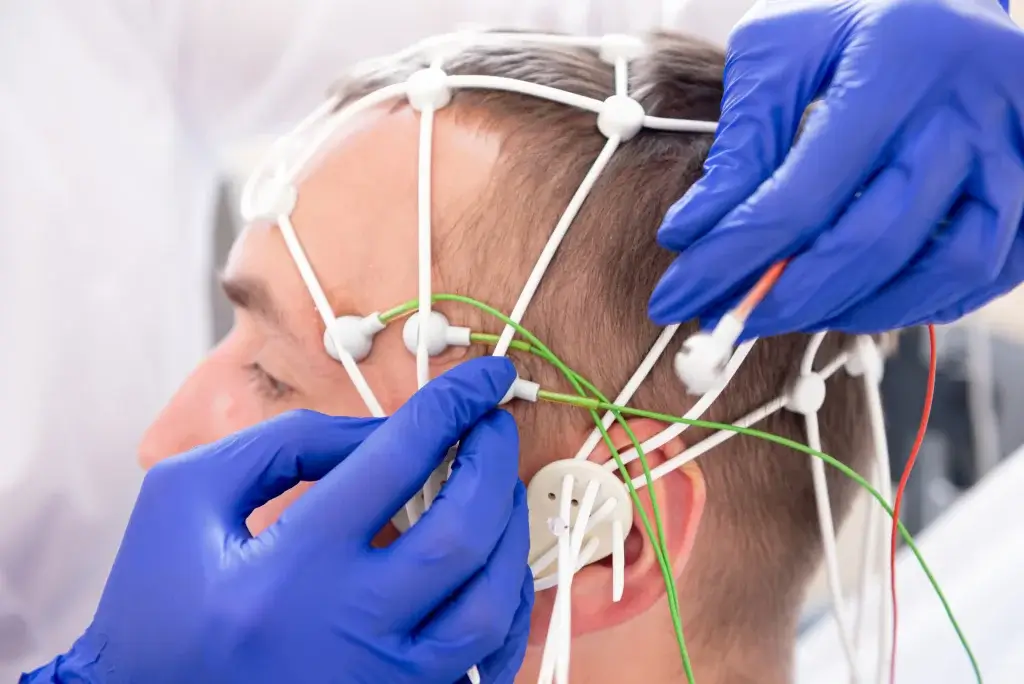 Close-up of hands placing an EEG headset on a man's head