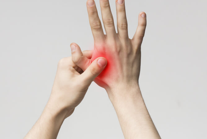 A person shows signs of pain, gripping their hand tightly, highlighting their extreme discomfort